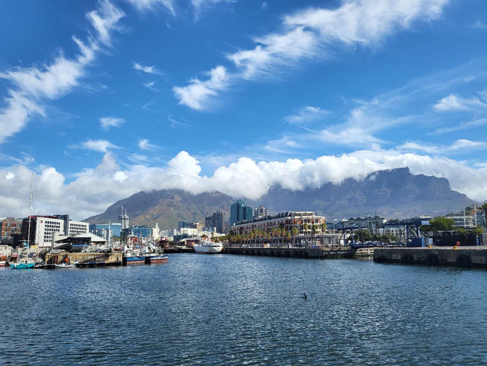 Boats and waterfront buildings beneath a mountain range